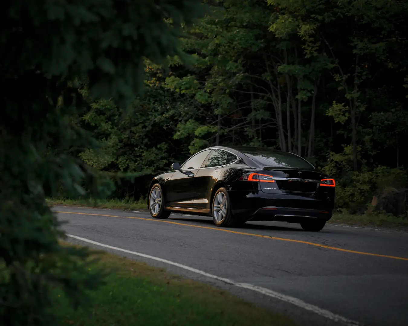 Electric vehicle driving on a road lined with trees